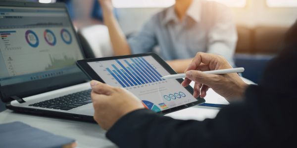 Person analyzing charts on a tablet and laptop.