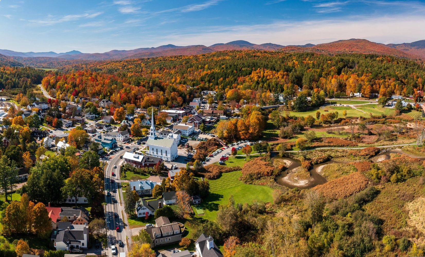 A picturesque autumn town nestled among colorful fall foliage and rolling hills.