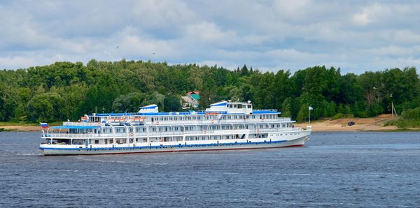 A white passenger boat cruising near a tree-lined shore.