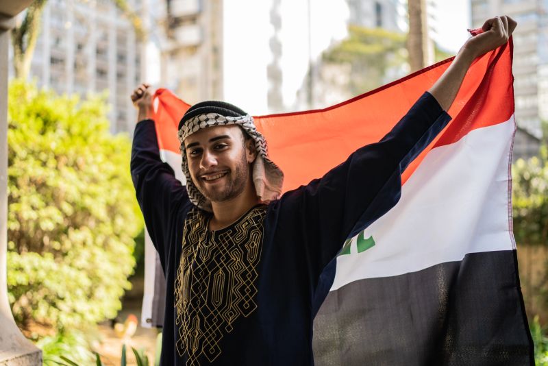 شَابٌّ عِرَاقِيٌّ يَرْفَعُ الْعَلَمَ الْعِرَاقِيَّ