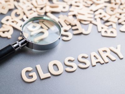 Magnifying glass over letters spelling ‘Glossary,’ representing terminology for massage retainers 