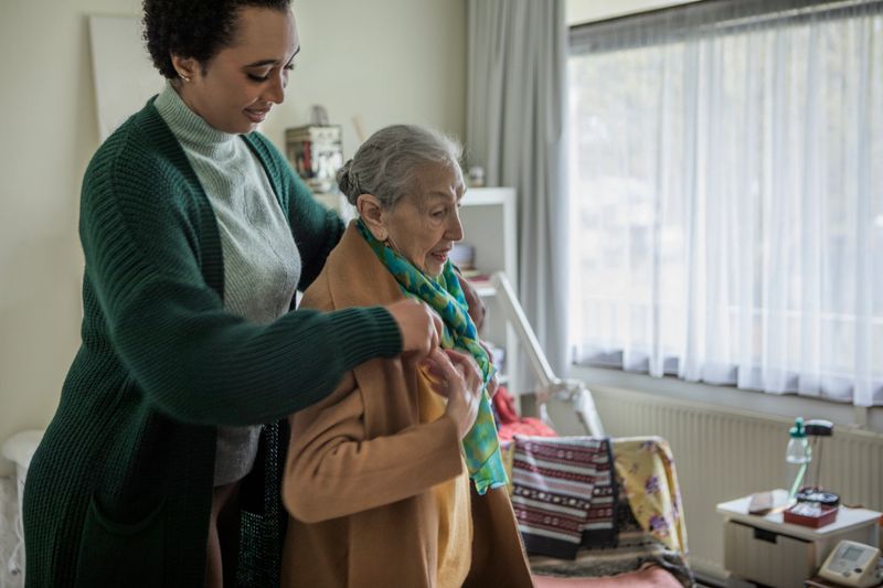 Cross generational community care volunteer helping an elderly client through her daily duties