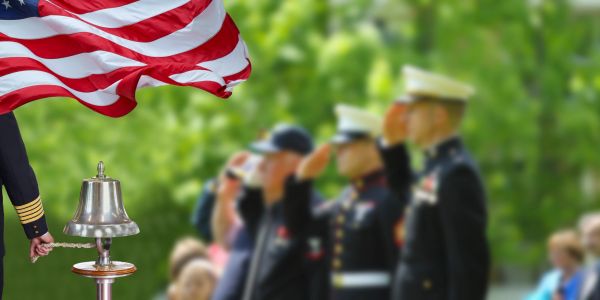 Military personnel saluting with an American flag waving.
