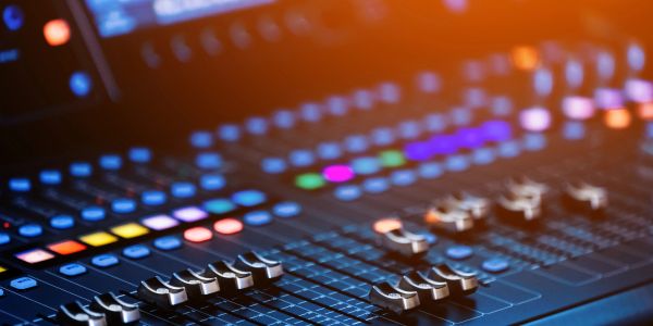 Close-up of a sound mixing console with colorful lights.