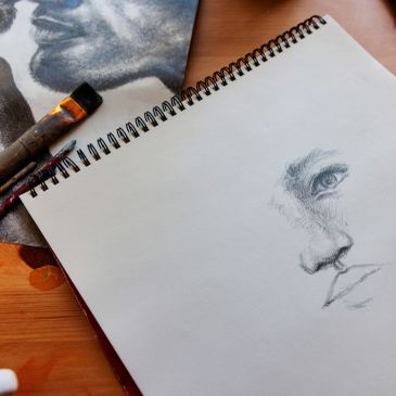 Sketch of a face in progress on a spiral notebook.