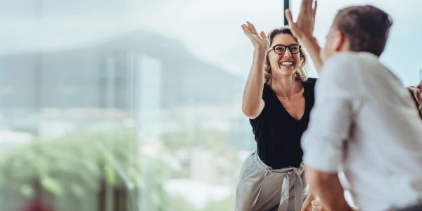 Two colleagues happily giving a high five in an office.