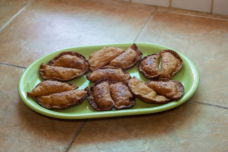 A colorful plate is full of freshly made homemade vegetarian dumplings with pasta dough on a countertop in a rustic kitchen. Food ready to eat.