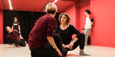 Two people having a conversation on the floor in a seated squat position. 