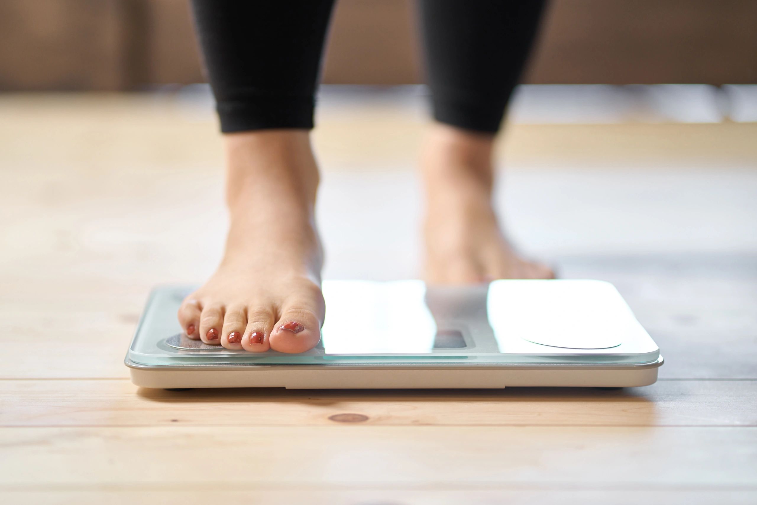 Person standing on a digital scale measuring weight.