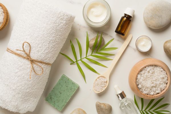 Spa essentials including towel, soap, oils, and bath salts arranged on white surface.