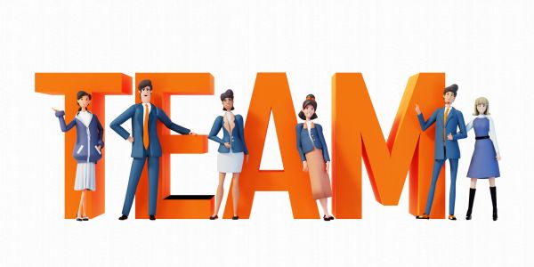 Business professionals posing with large orange letters spelling TEAM.