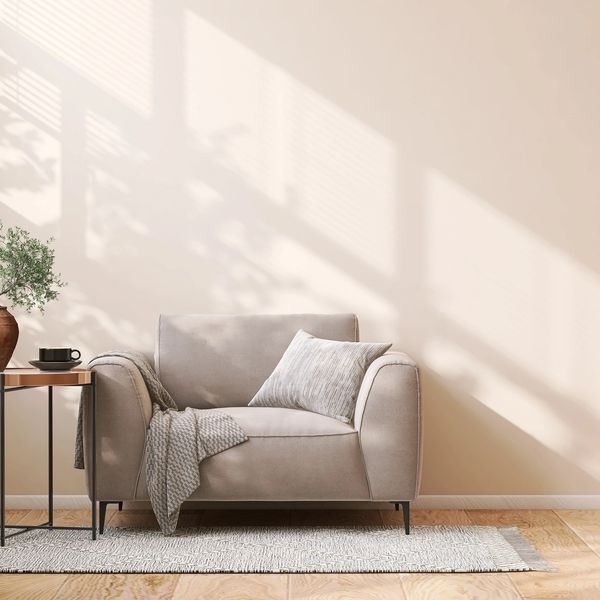 Cozy beige armchair with pillow and throw blanket.