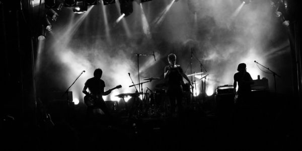 Silhouetted band performing on stage with dramatic lighting and smoke effects.