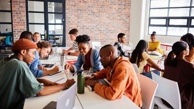 Group of diverse students studying together while sitting around a table between classes at school