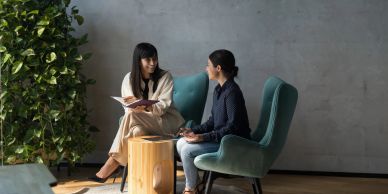 Two women engaged in conversation in a modern office space.