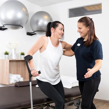 A woman with crutches receiving physical therapy support.