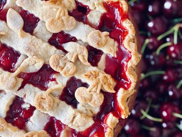 Close-up of cherry pie with lattice crust and cherries.