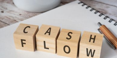 Wooden blocks spelling "CASH FLOW" on a notebook.