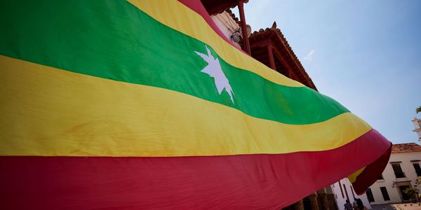 Large colorful flag with green, yellow, and red stripes waving outdoors.