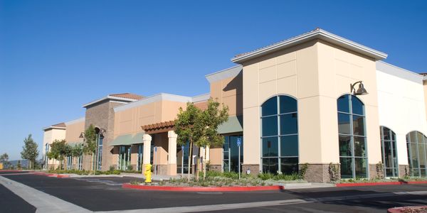 Modern commercial building with large windows under a clear blue sky.
