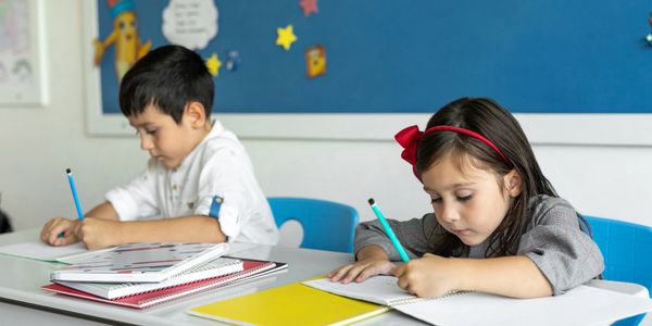 Two children focused on writing in a classroom.