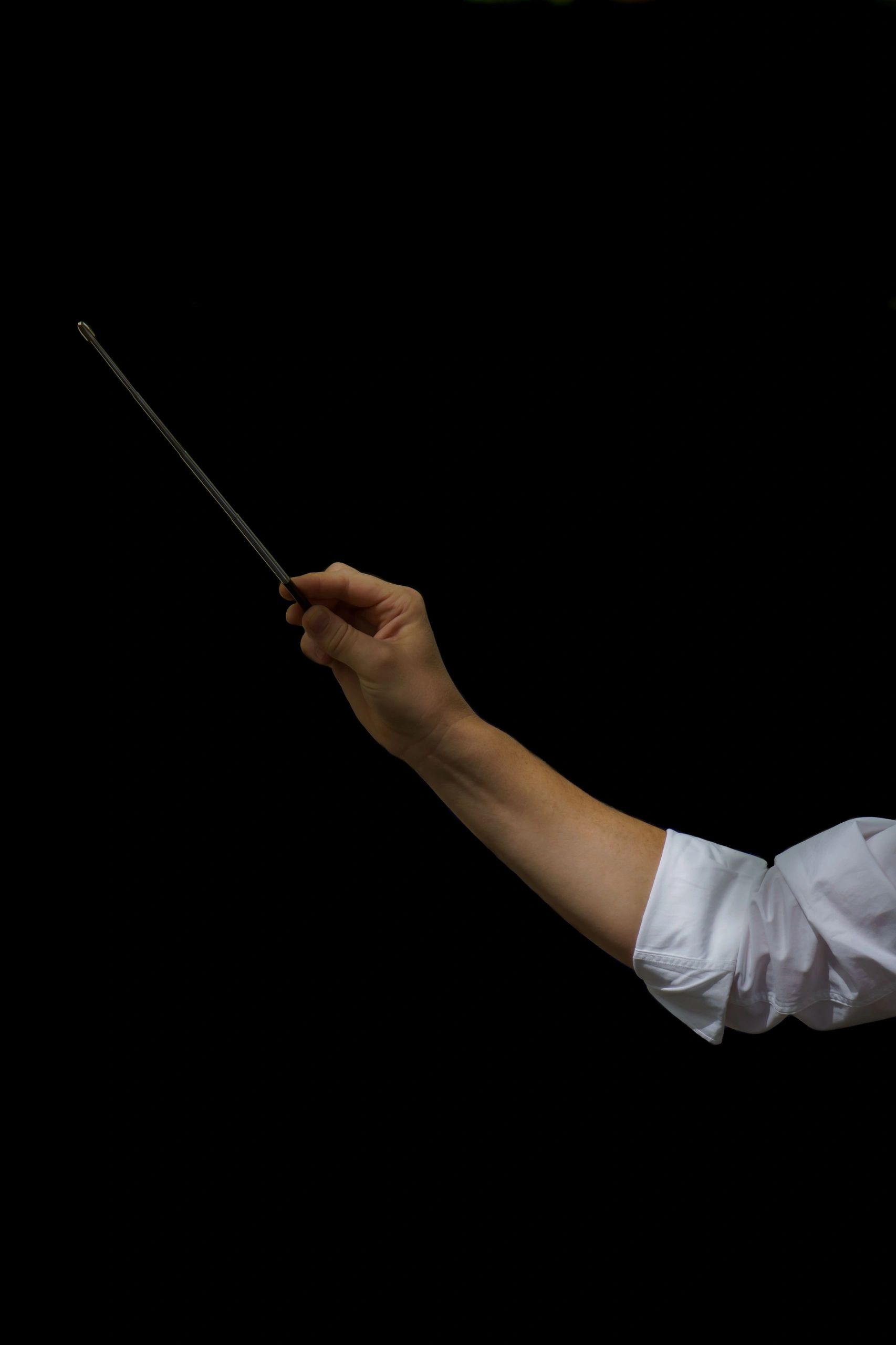 Orchestra conductor hands holding baton close-up
