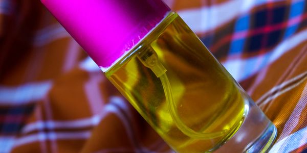 A close-up of a perfume bottle with yellow liquid and a pink cap.