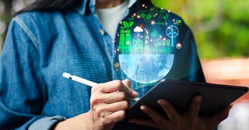 Person using a tablet with digital sustainability icons floating above.
