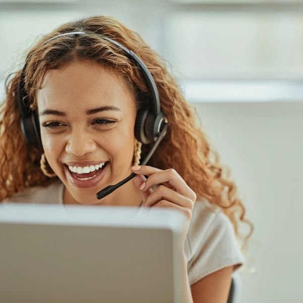 Smiling woman with headset engaged in a video call.