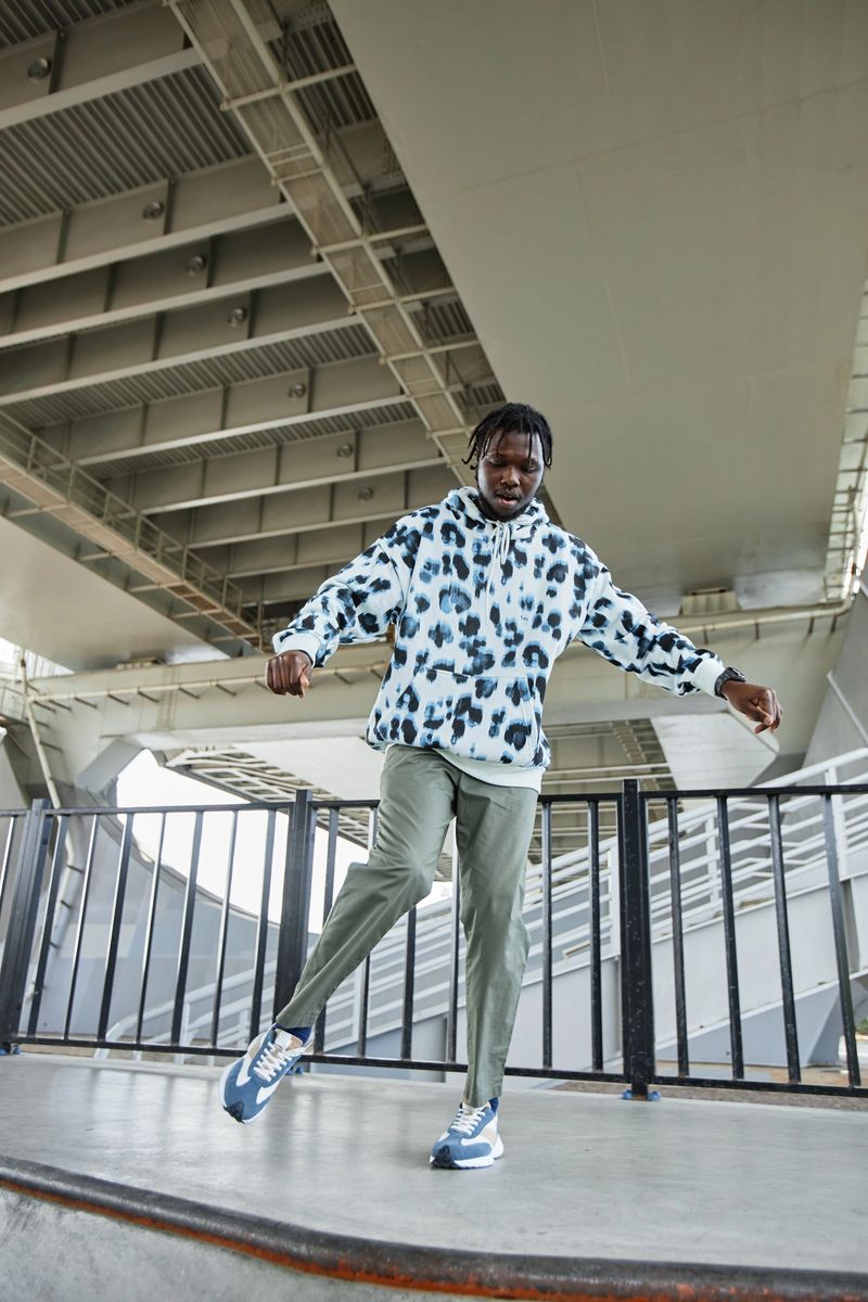 Vertical full length portrait of young black man dancing outdoors in urban area