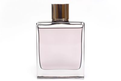 Elegant rectangular perfume bottle with light pink liquid and gold cap.