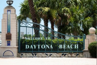 Entrance gate welcoming visitors to Daytona Beach with palm trees in the background.