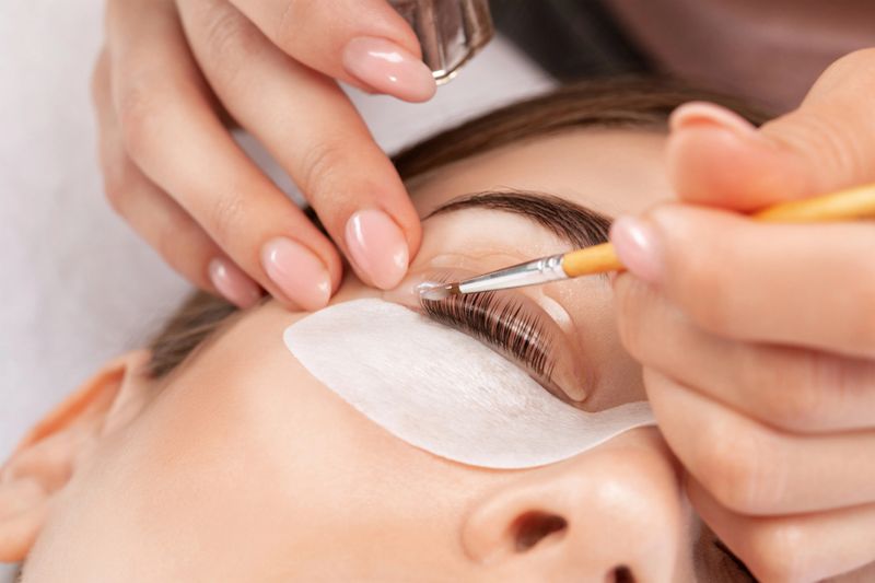 Make-up artist makes the procedure of lamination and dyeing of eyelashes to a beautiful woman in a beauty salon. Eyelash extensions. Eyelashes close-up