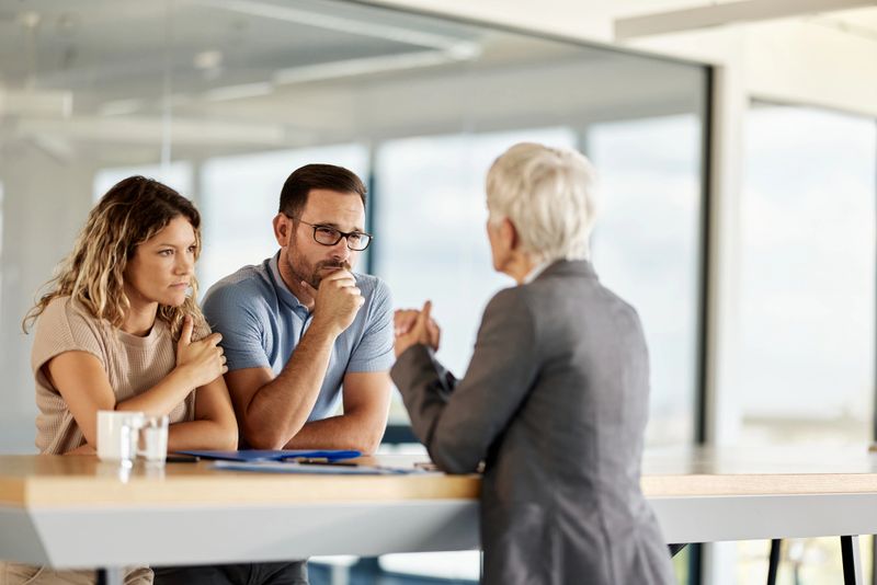 Young couple communicating with their real estate agent during a meeting in the office. Focus is on man.