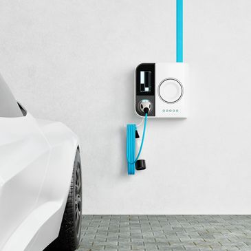White electric car charging at a modern wall-mounted station.