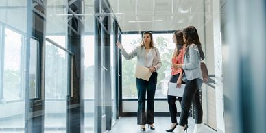 Three professional women discussing plans in a modern office space.