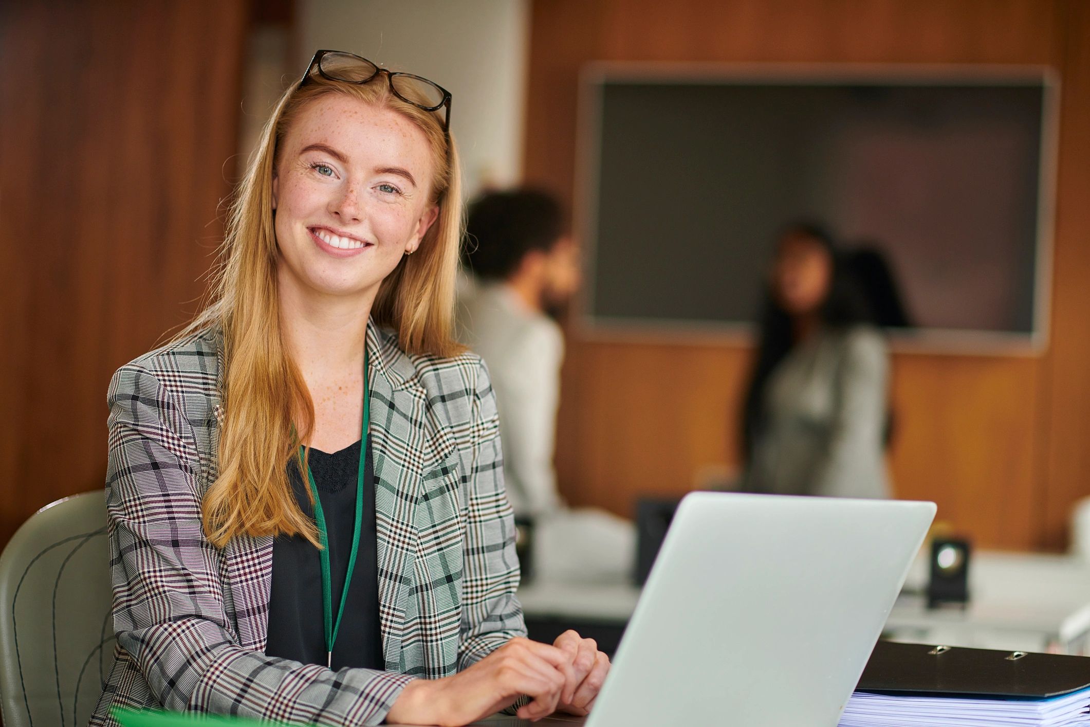 Smiling woman working on a laptop in an office setting. Bachelor in Gastronomy, Gastronomy Degree, Swiss Hospitality Education