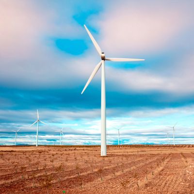 Wind turbines standing tall in a dry field under a partly cloudy sky.