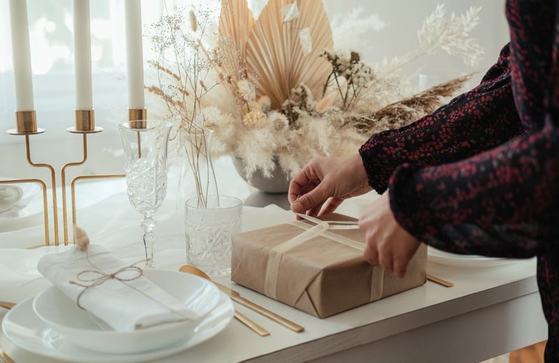 Close up photo of woman hands setting the table and preparing gifts for new year dinner party at home.