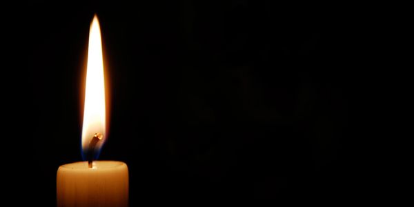A single lit candle glowing in the dark.