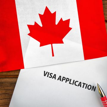 Canadian flag above a visa application form with a pen.