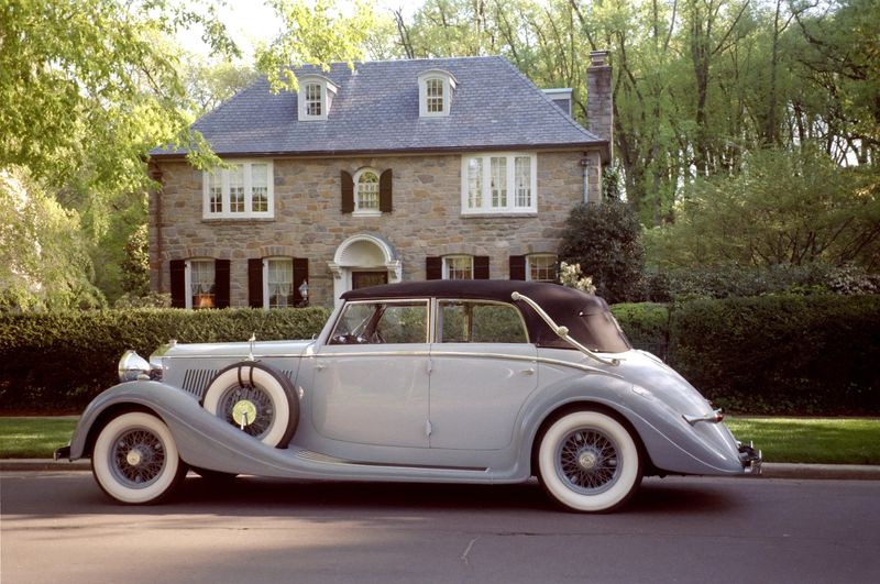 Photo of vintage automobile parked in front of a mansion.