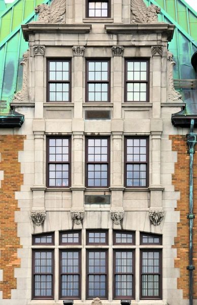 Facade of a historic building with symmetrical windows and ornamental stone carvings.