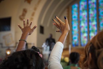 Hands raised in worship inside a church.