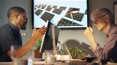 Two men discussing solar panel designs in an office.
