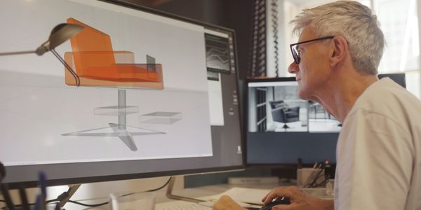 Man designing a chair using 3D modeling software at his desk.