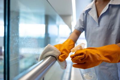 Person cleaning a glass railing with gloves.