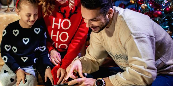 Family enjoying Christmas together by the decorated tree with gifts.