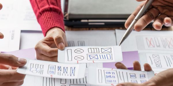 People reviewing UI wireframes on paper during a collaborative meeting.