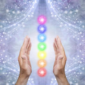 Hands surrounding colorful chakra energy points.